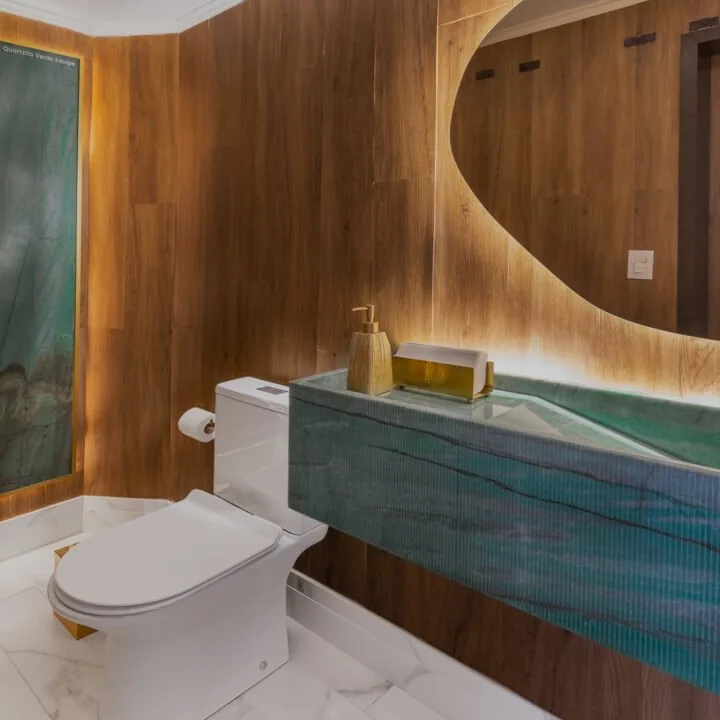 Lavabo com bancada esculpida em quartzito verde e painel curvo de madeira