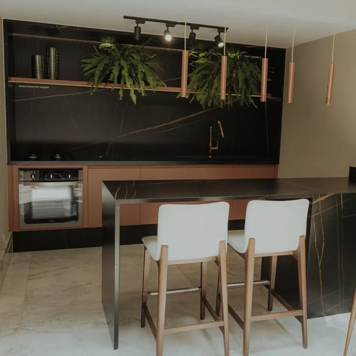 Cozinha com bancada e painel em mármore preto e bancos altos