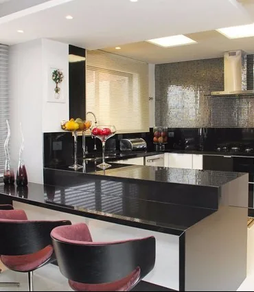 Cozinha com bancada em granito preto e banquetas coloridas
