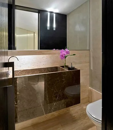 Lavabo com bancada esculpida em mármore marrom e espelho amplo